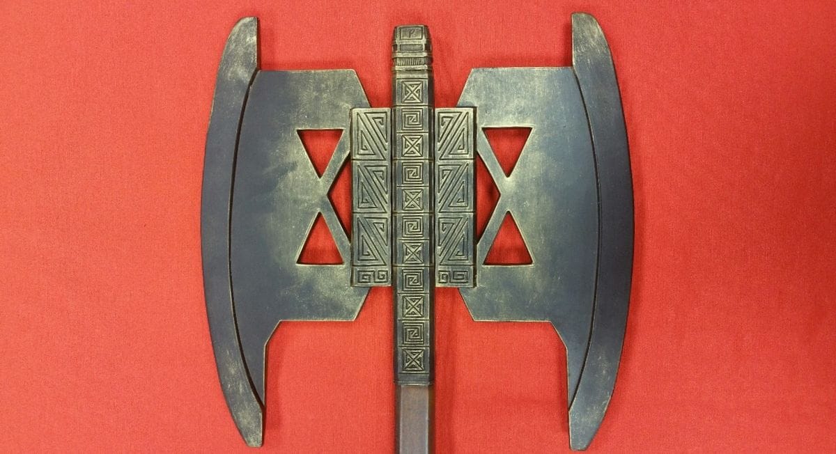 Detalle de cabeza del Hacha de combate de Gimli de El Señor de los Anillos con grabados expuesta en fondo rojo. Vendida por Espadas y más