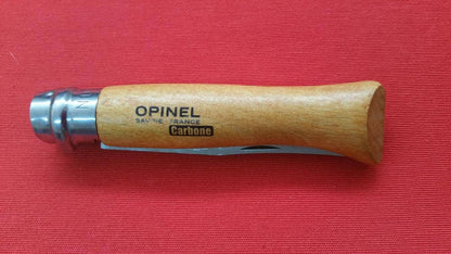 Detalle de mango de navaja opinel abierta expuesta en tela roja. Vendida por Espadas y más